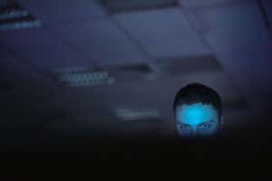 Un hombre en un cuarto oscuro mirando una pantalla