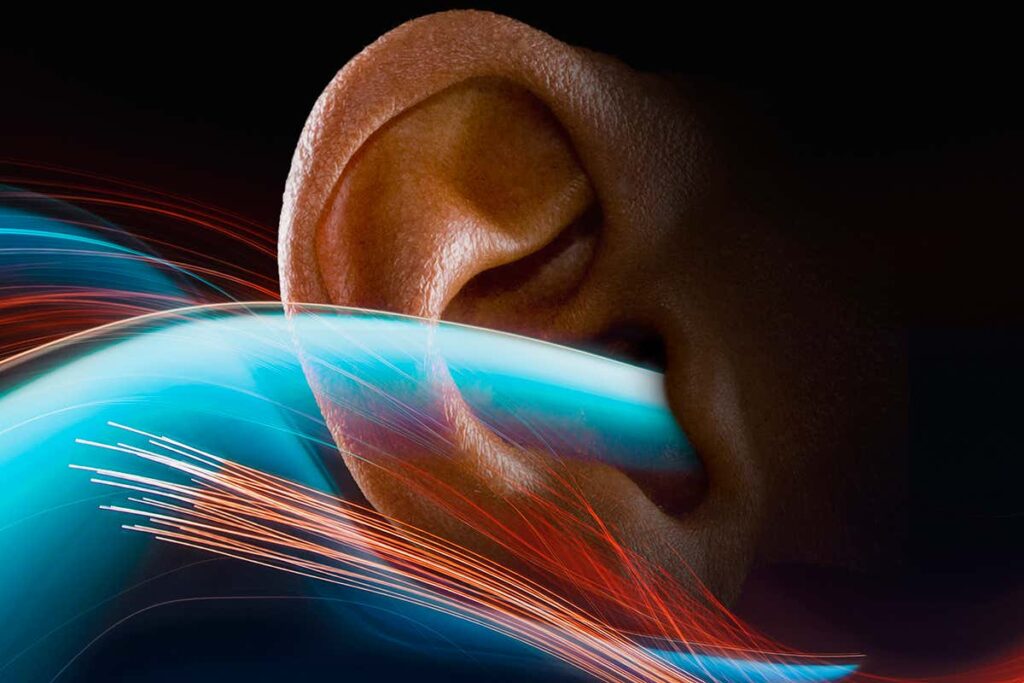 Light trails represent sound waves as they stream into a human ear.